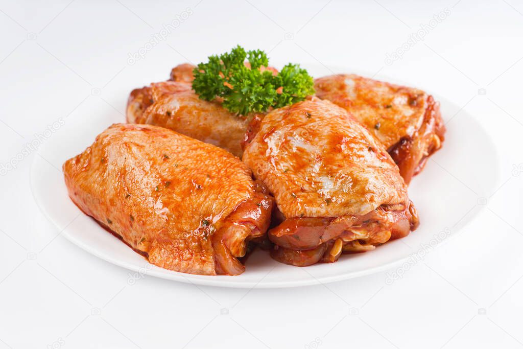 Marinated chicken thigh on a white plate on a light background. Chicken for retail.Precooked food.Convenience foods.delicious fried chicken thigh
