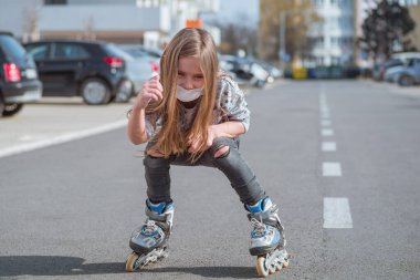 Yüzündeki yaşlılıktan koruyucu maske. Yüzüne koruyucu maske takmış patenci bir kız sokakta kayıyor..