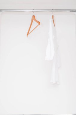 Boş rampalı gardırop. Mağazada indirim var. Beyazlar. Dolabında beyaz tişört ve boş rampalar asılı modern gardırop.