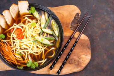 Çin eriştesi, et ve sebze parçaları. Mutfak tahtasındaki siyah kasede. Kızarmış Çin eriştesi, tavuk, sebze..