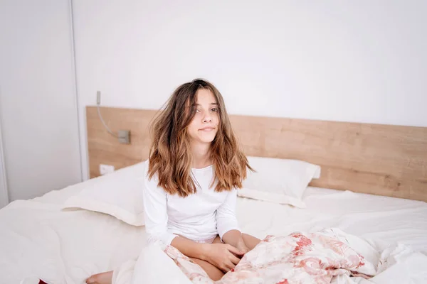 The girl is in bed in the morning, rejoices at waking up with a good mood.Portrait pretty young girl on bed in modern apartment in the morning. She keeps eyes closed and looks satisfied