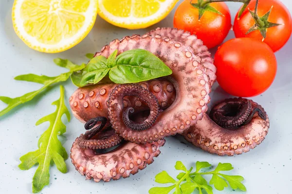 Sea food.Raw octopus tentacles in a blue plate with slices of lemon salad and small tomatoes.Close up of raw octopus.