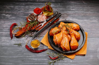 Uygun yemek, özel yemek. Çiğ organik tavuk bacağı. Ahşap bir kesme tahtasının üzerinde terbiye etmek için gerekli malzemeler..