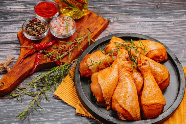 Convenience food,pree cooked.Raw organic chicken legs with ingredients for cooking marinatingon a wooden cutting board over dark slate, stone or concrete background.Top view.