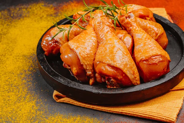 Top view.Convenience food,pree cookedMarinated Chicken Drumstick on Black Ceramic Round Roasting Plate Raw Chicken for Grilling with Spices for Cooking.