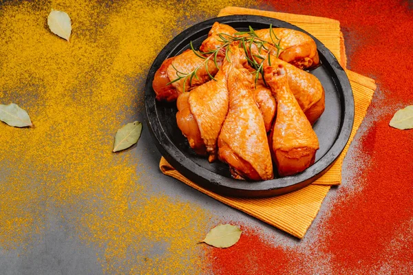 Top view.Convenience food,pree cookedMarinated Chicken Drumstick on Black Ceramic Round Roasting Plate Raw Chicken for Grilling with Spices for Cooking.