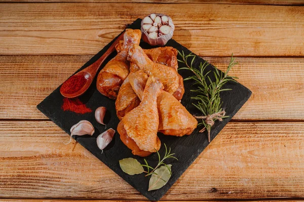 Top view.Convenience food,pree cookedMarinated chicken dramstick on a black ceramic plate. Raw chicken for grilling with spices for cooking.