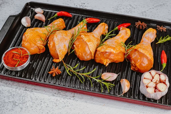 Marinated chicken dramstick on a griddle pan. Top view.Convenience food,pree cooked.Raw chicken for grilling with spices for cooking.