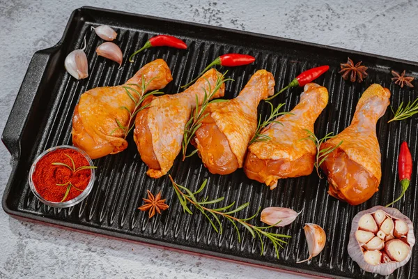 Convenience food,pree cooked.Raw chicken for grilling with spices for cooking.Marinated chicken dramstick on a griddle pan. Top view.