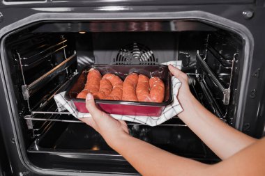 Uygun yemek, prematüre. Kız ızgara sosisleri fırının içindeki pakete koyuyor. Fırında pişirilmiş..
