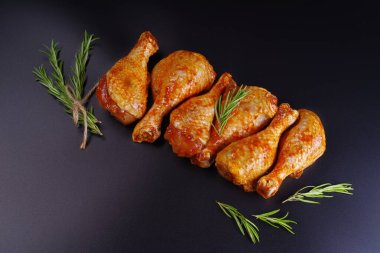 Taze tavuk bacağı. Baharatlı çiğ tavuk budu ve siyah arka planda yeşil biberiye. Şişlerin üzerinde çiğ tavuk şişi. Uygun yemek, önceden pişirilmiş..