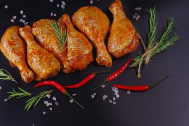 Taze tavuk bacağı. Baharatlı çiğ tavuk budu ve siyah arka planda yeşil biberiye. Şişlerin üzerinde çiğ tavuk şişi. Uygun yemek, önceden pişirilmiş..