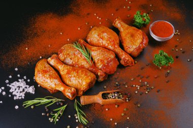 Taze tavuk bacağı. Baharatlı çiğ tavuk budu ve siyah arka planda yeşil biberiye. Şişlerin üzerinde çiğ tavuk şişi. Uygun yemek, önceden pişirilmiş..