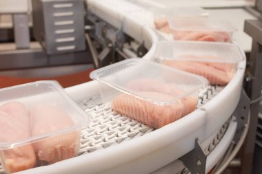 Taşıma bandı gıdası. Etten yiyecek üretimi için fabrika. Paketleme ile üretim hattı. Konveyör üzerinde plastik paketlenmiş et ürünleri tavuğu..