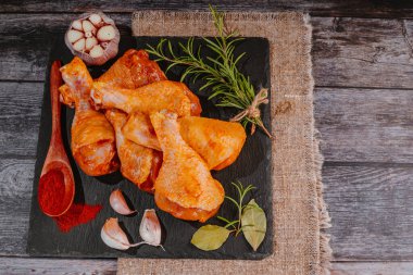 Çiğ salamura edilmiş tavuk budu baharat serpiştirilmiş, acı biber parçaları, körfez yaprakları pişmeye hazır, yukarıdan manzaralı. Baharatlı kırmızı salamura edilmiş tavuk salamura edilmiş tavuk. Çiğ terbiye edilmiş tavuk eti. Çiğ but..