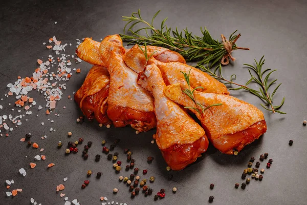 Raw marinated chicken drumsticks sprinkled with spice, chili pepper pieces, bay leaves prepared to cook in a dish, view from above.Drumstick marinated chicken in red marinade with spices. Raw marinated chicken meat. Raw drumstick.