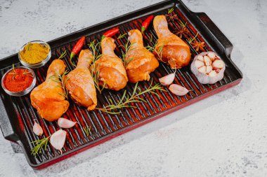 Izgara tavasında baharatlı çubuk. Çiğ salamura edilmiş tavuk eti. Baharatla marine edilmiş tavuk budu, acı biber parçaları serpiştirilmiş körfez yaprakları, yukarıdan görülmeye hazır..