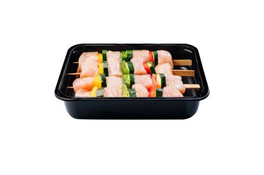 Sebzeli, biberli ve kabaklı tavuk şişi. Siyah bir konteynırda tavuk kebabı, beyaz bir tabakta perakende için..