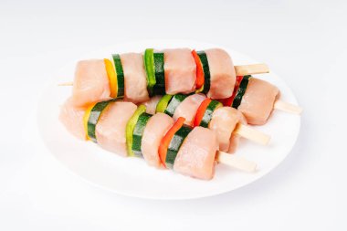 Arka planda beyaz bir tabakta şiş tavuk şişleri. Sebzeli tavuk şişleri, tatlı biberli..