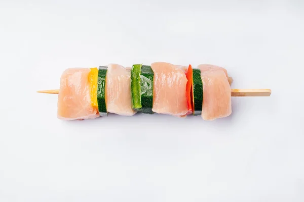 Raw chicken skewers.One skewer with four chicken fillet slices with bell peppers and zucchini vegetables.