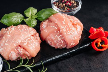 Fesleğen yapraklı iki tavuk burger ve siyah arkaplanda siyah seramik bir tahtada kırmızı dolma biber. Fast food. Uygun yemekler, hızlı ev yemekleri..