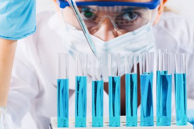 Kadın araştırmacı, test tüpleriyle laboratuarda çalışan bir laboratuvar asistanı mikropipet doldurma tüpü kullanıyor. Aşı örnekleri üretiyor. Aşılar ve uyuşturucular laboratuvarında geliştirme.