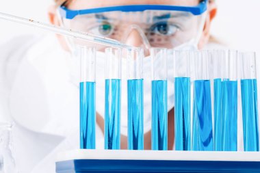 Laboratuvarda test tüpleri bulunan bir laboratuvar asistanı kullanarak bir kadın araştırmacının yakın çekiminde aşı örnekleri üretilir. Aşıların geliştirilmesi, laboratuvarda uyuşturucu.