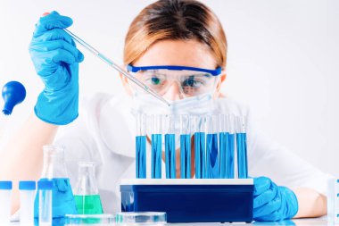 Kadın araştırmacı, test tüpleriyle laboratuarda çalışan bir laboratuvar asistanı mikropipet doldurma tüpü kullanıyor. Aşı örnekleri üretiyor. Aşılar ve uyuşturucular laboratuvarında geliştirme.