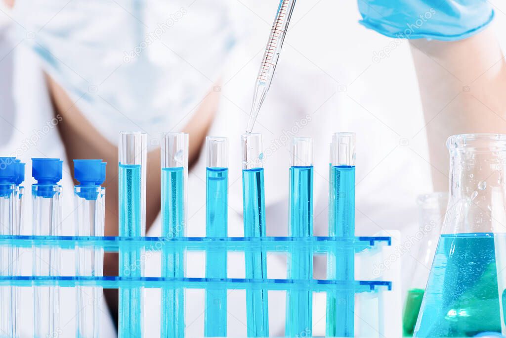 Female Research Scientist Uses Micropipette Filling Test Tubes.A laboratory assistant in a laboratory with test tubes produces vaccine samples. Development in a laboratory of vaccines, drugs.