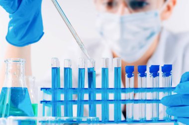 Kadın araştırmacı, test tüpleriyle laboratuarda çalışan bir laboratuvar asistanı mikropipet doldurma tüpü kullanıyor. Aşı örnekleri üretiyor. Aşılar ve uyuşturucular laboratuvarında geliştirme.