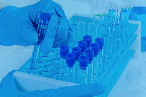 A laboratory assistant in a laboratory with test tubes produces vaccine samples. Development of vaccines and drugs.Close-up of a female researcher using a micropipette filling test tubes.