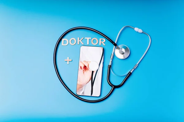Female doctor chatting online with patients.Copy space. Stethoscope on a blue background with place for text, online doctor. Calling a doctor by phone.Health concept. The doctor can examine the patient via video call.