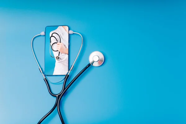 Teletıp konsepti, kadın doktorla görüntülü sohbet ediyor. Hastalarla çevrimiçi sohbet ediyor. Metin için mavi bir arkaplanda steteskop, çevrimiçi doktor. Telefonla doktor çağırmak.