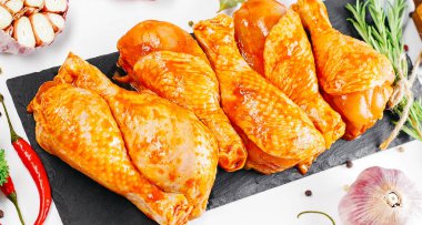 Ogranik yemek ve sağlıklı beslenme kavramı. Tavuk budu pişirme. Biberiye ve biberiyeli salamurada çiğ tavuk bacağı..