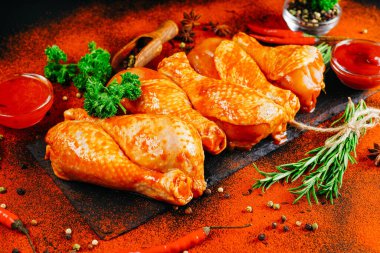 Çiğ tavuk bacağı, otlar ve baharatlarla. Ogranik yiyecekler ve sağlıklı beslenme konsepti. Salamurada tavuk budu pişirme. Biberiye ve biberiyeli çiğ tavuk bacağı..