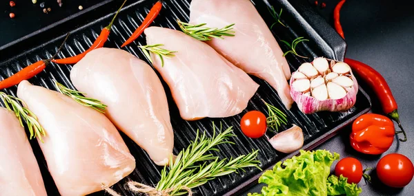 暗い背景にスパイスや野菜とフライパンで鶏の切り身 調理のための作品にカット鶏の肉を生 コピースペースでトップビュー — ストック写真