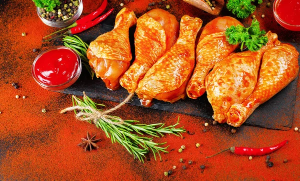 Convenience food, precooked.Cooking chicken drumsticks.Top view.Chicken legs on a black background with spices of rosemary, red hot pepper and paprika.