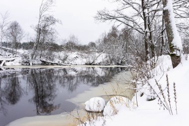 Karlı ormanlı kış manzarası, donmuş nehir ve sarı aksanlı