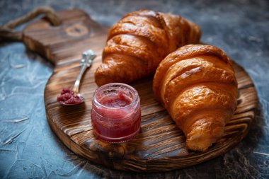 Antika ahşap tahtanın üzerinde taze kruvasan ve meyve reçeli taşralı stili.