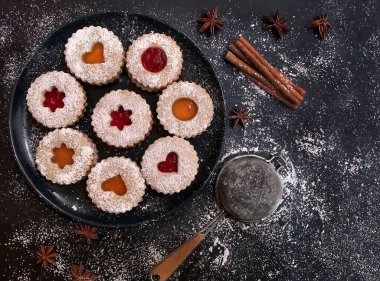 Kayısı ve koyu arkaplanda çilek reçelli ev yapımı Noel Linzer kurabiyeleri. Üst Manzara. Düz yatıyordu.