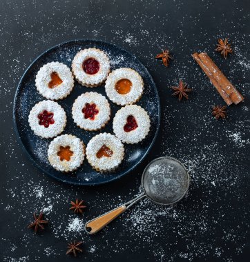 Kayısı ve koyu arkaplanda çilek reçelli ev yapımı Noel Linzer kurabiyeleri. Üst Manzara. Düz yatıyordu.