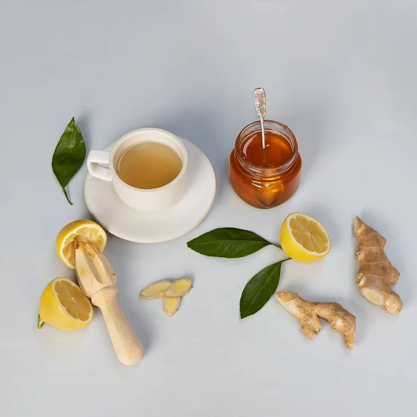 Ginger, honey and lemon healthy herbal tea on light grey background.