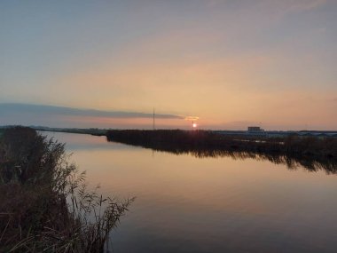 Zevenhuizen 'de Rotte nehrinin üzerinde gün batımı Tweemanspolder' da Molenviergang 'ın yel değirmenleriyle