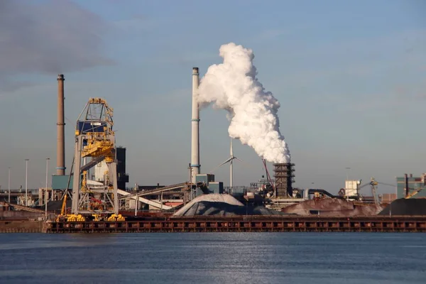 IJmuiden 'daki Tata çelik fabrikasındaki borulardan gelen su buharı kömür ve demir cevheri taşıyan gemilerin boşaltıldığı yerde.