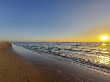 Güneş, Hollanda 'daki renkli gökyüzü ile Katwijk plajında denize batar.