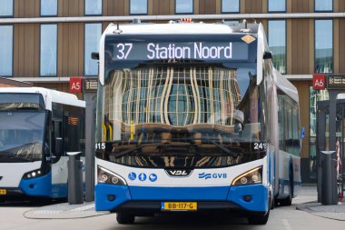 Amsterdam, Hollanda - 11 Ağustos 2025 - Amsterdam 'ın mavi ve beyaz şehir otobüsleri Amstel istasyonunda yerel hizmet için. 