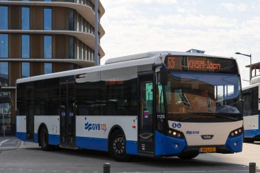 Amsterdam, Hollanda - 11 Ağustos 2025 - Amsterdam 'ın mavi ve beyaz şehir otobüsleri Amstel istasyonunda yerel hizmet için. 