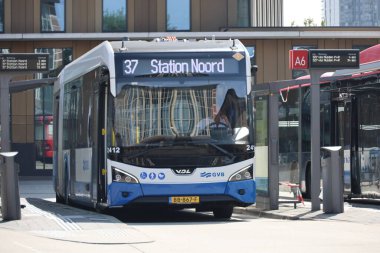 Amsterdam, Hollanda - 11 Ağustos 2025 - Amsterdam 'ın mavi ve beyaz şehir otobüsleri Amstel istasyonunda yerel hizmet için. 