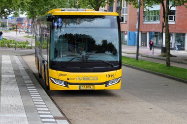 Sarı Qbuzz otobüsü Hollanda 'daki Heerenveen istasyonunda Frizya Kaynağı' na doğru koşuyor.
