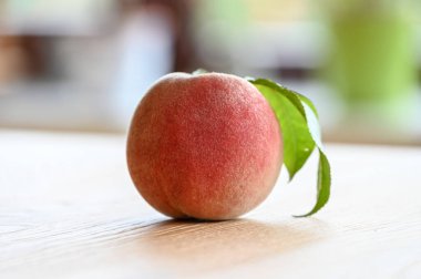 Tahta bir masada tek bir şeftali. Yakın plan.